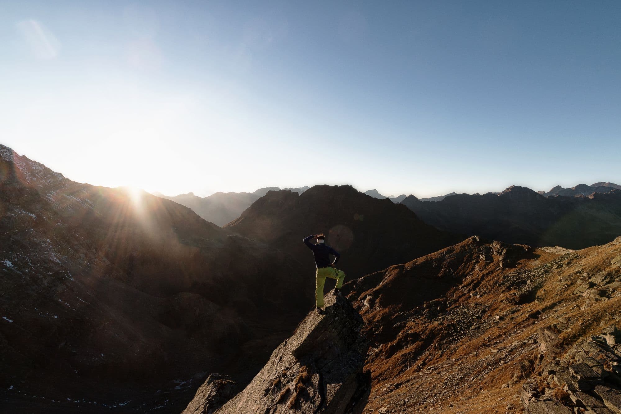 A man taking in the view from a mountain trail at first light
